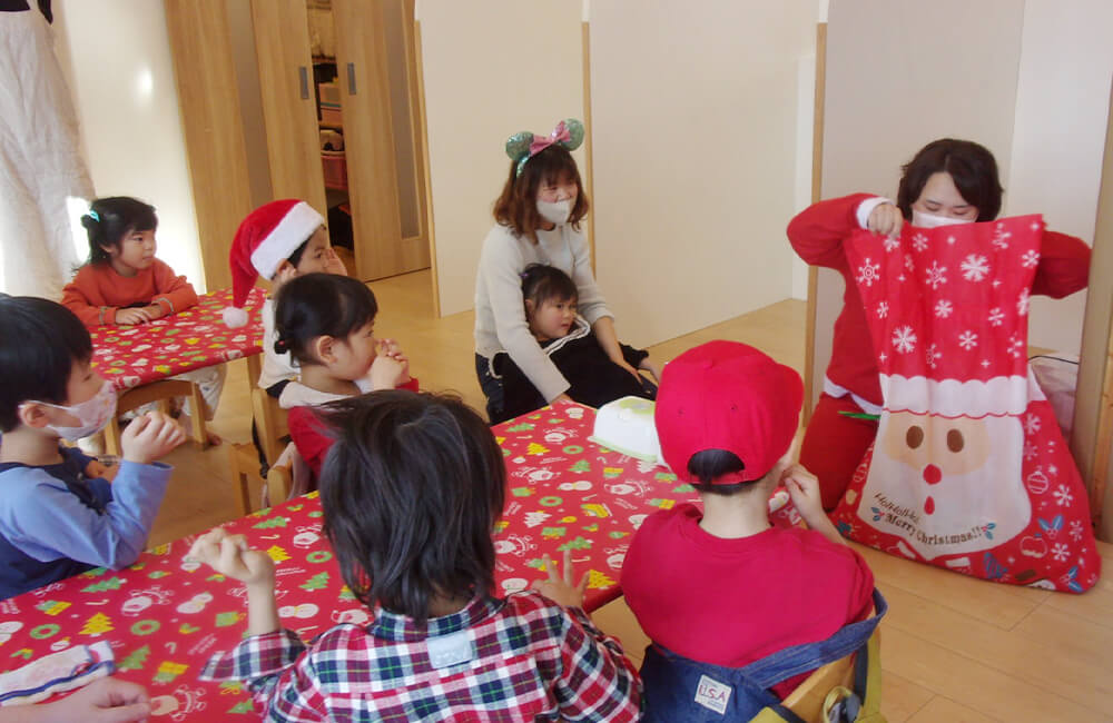 12月はクリスマス会！写真はサンタさんからオレンジで遊ぶおもちゃがプレゼントされている様子です（オレンジ）