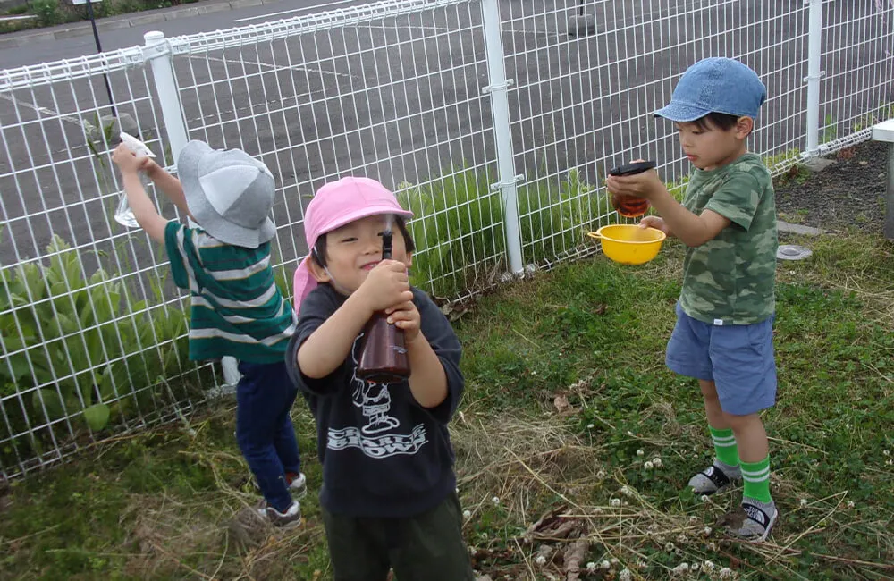 外遊びも行います。写真はみんなで水遊びをしている様子です。（オレンジ2）